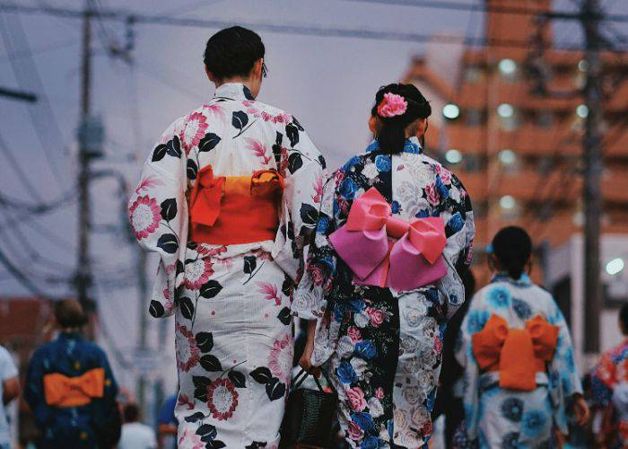 Two people wearing kimono walking together at a Japanese festival.